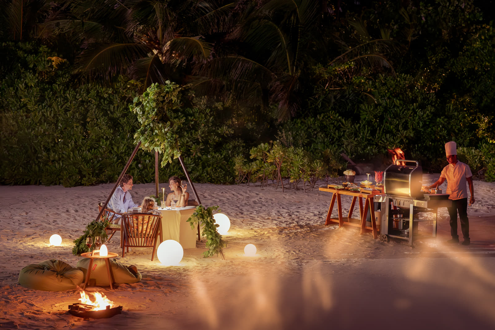 Night beach BBQ scene with a chef at the grill